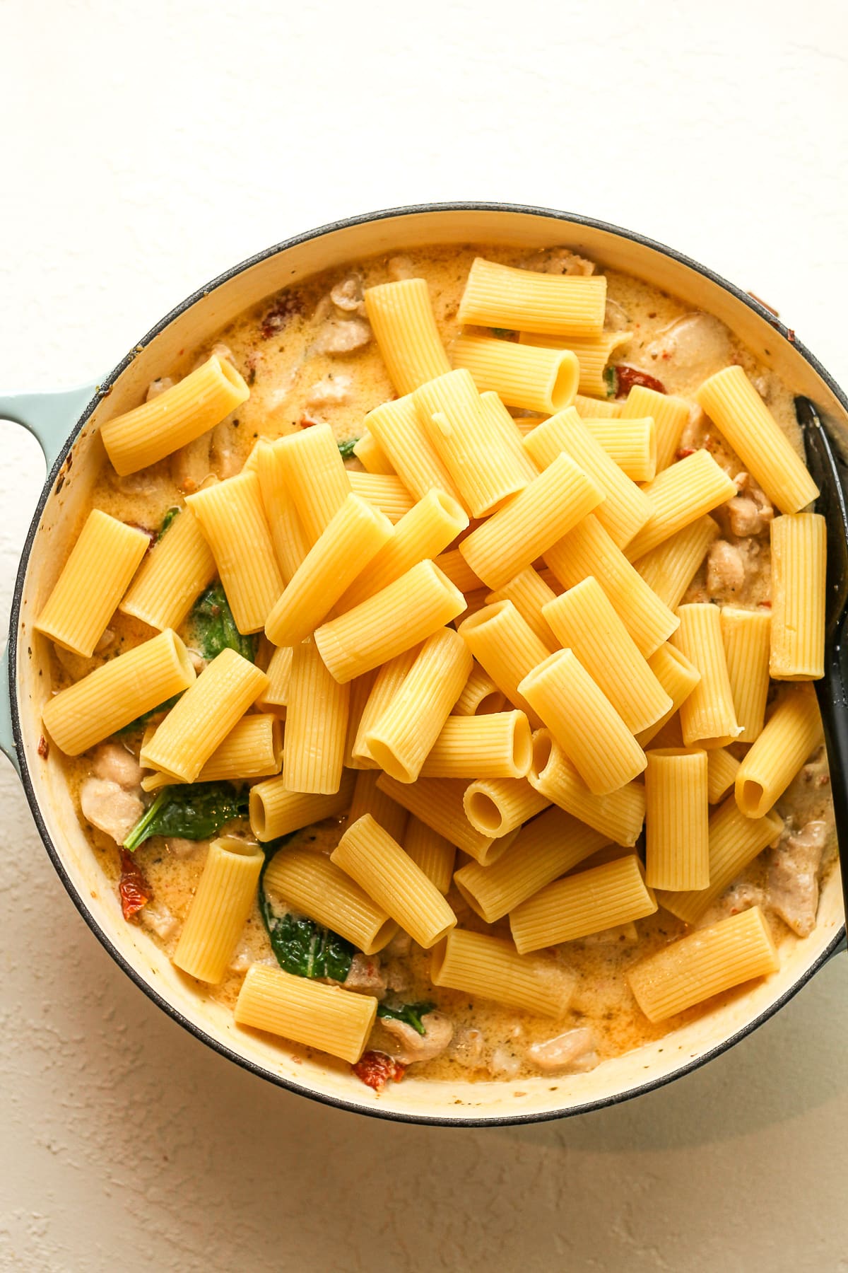 A pot of the cheesy sauce and rigatoni pasta on top.