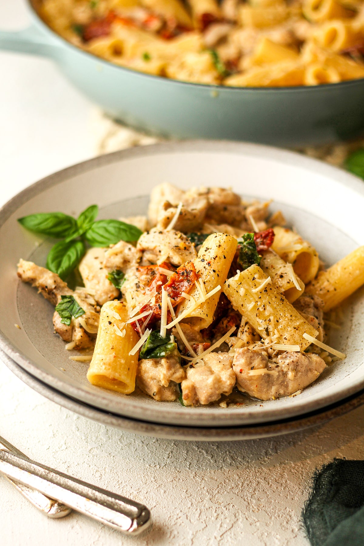 Side view of a bowl of pasta, chicken, and veggies.