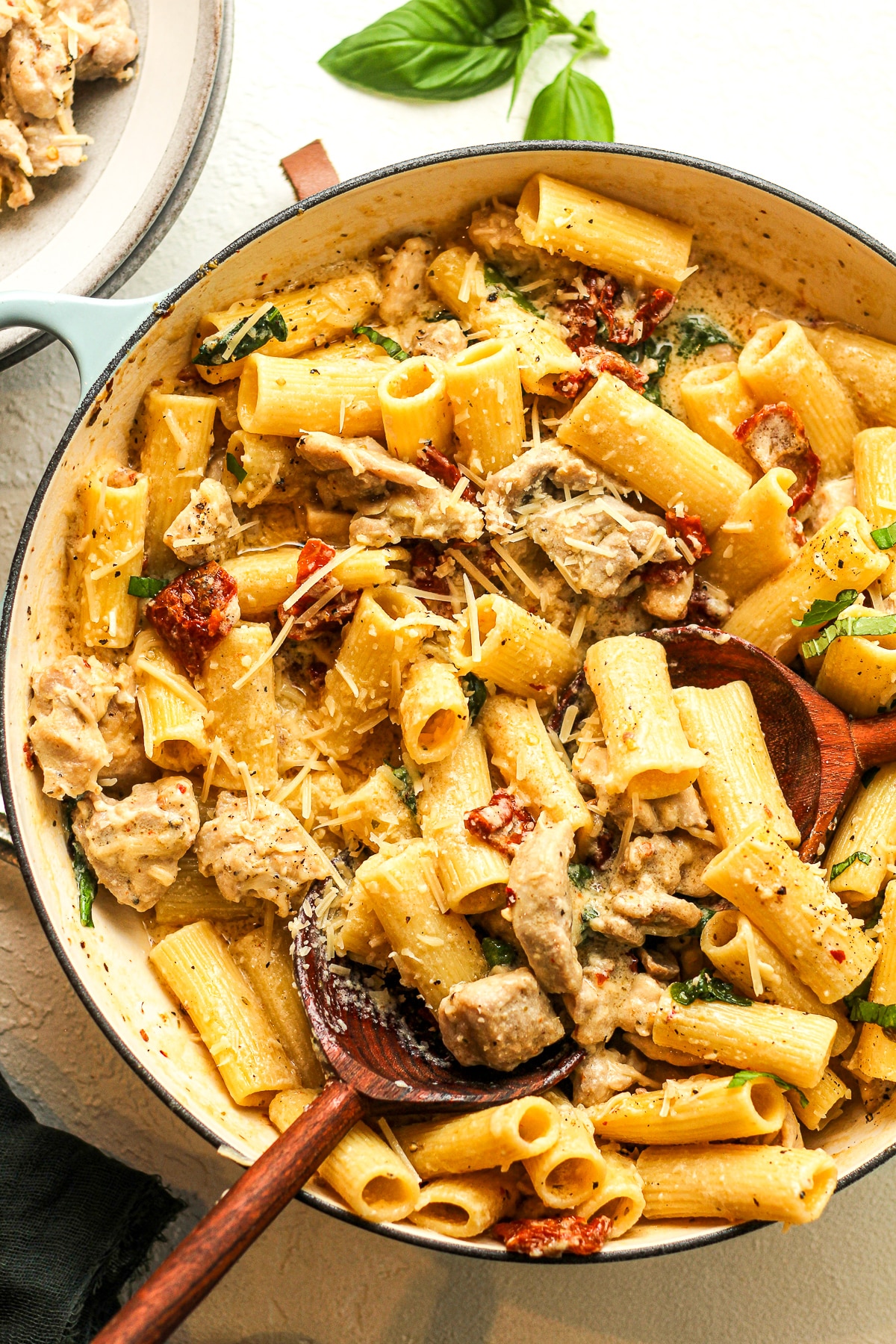 A pot of marry me chicken pasta with wooden spoons.