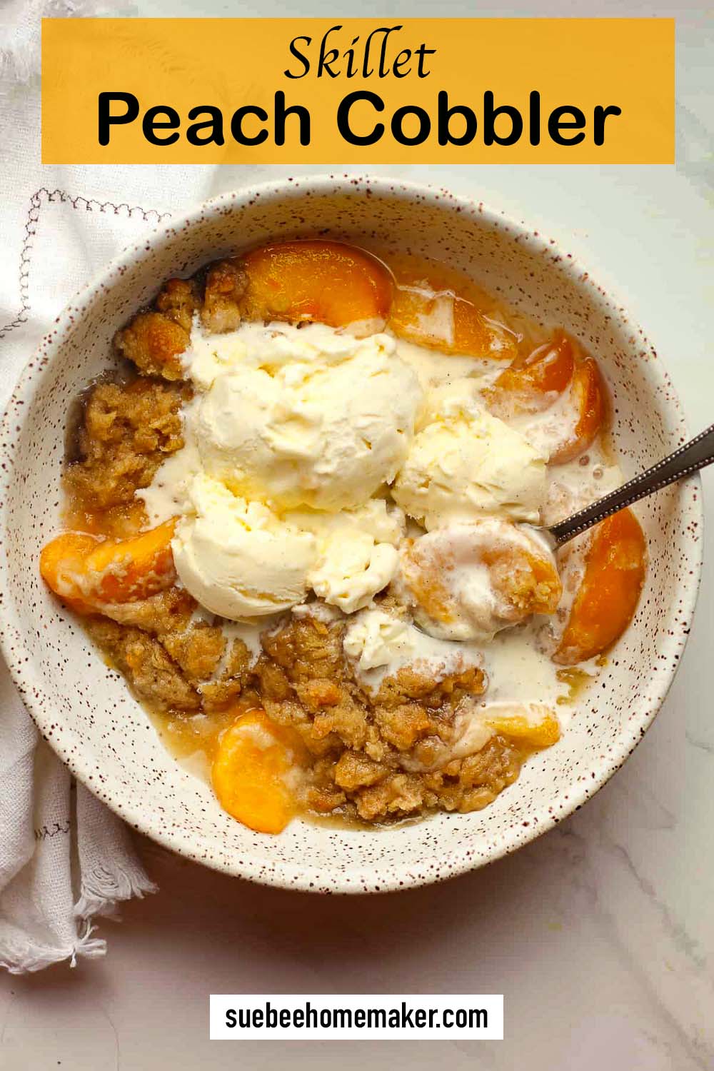 A bowl of skillet peach cobbler with scoops of vanilla ice cream.