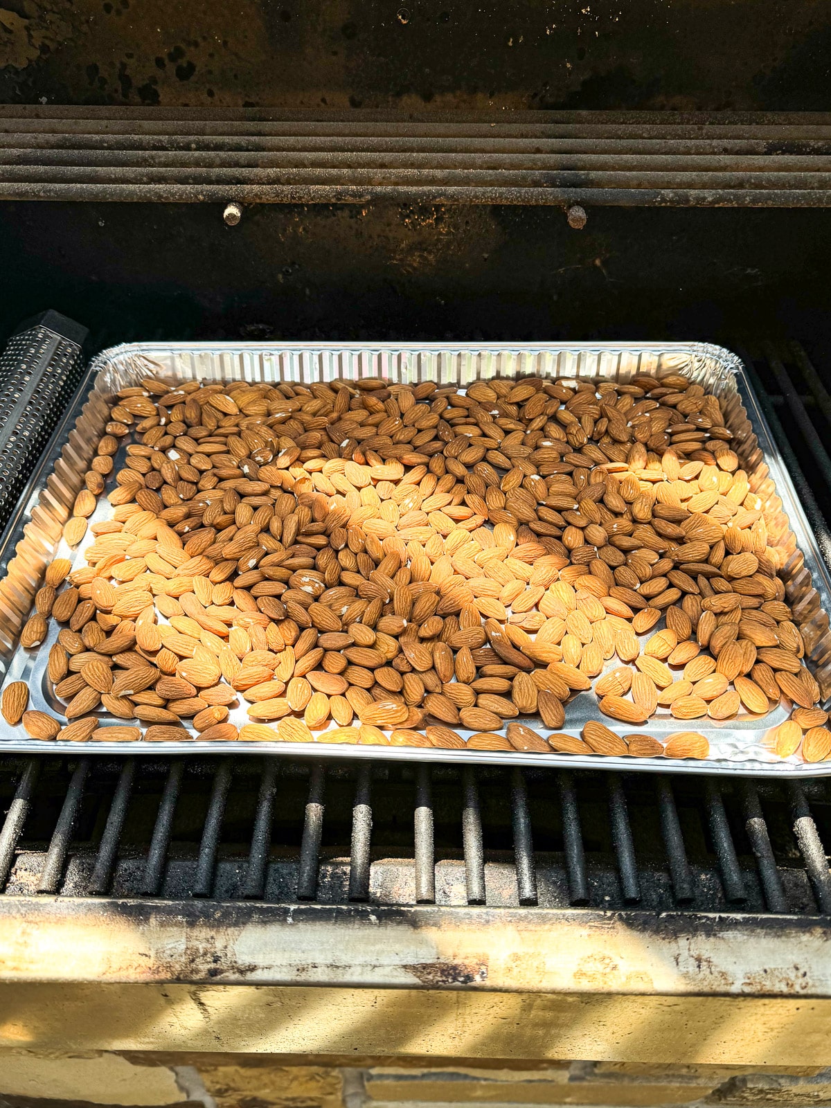 The almonds on a disposable pan on a smoker.