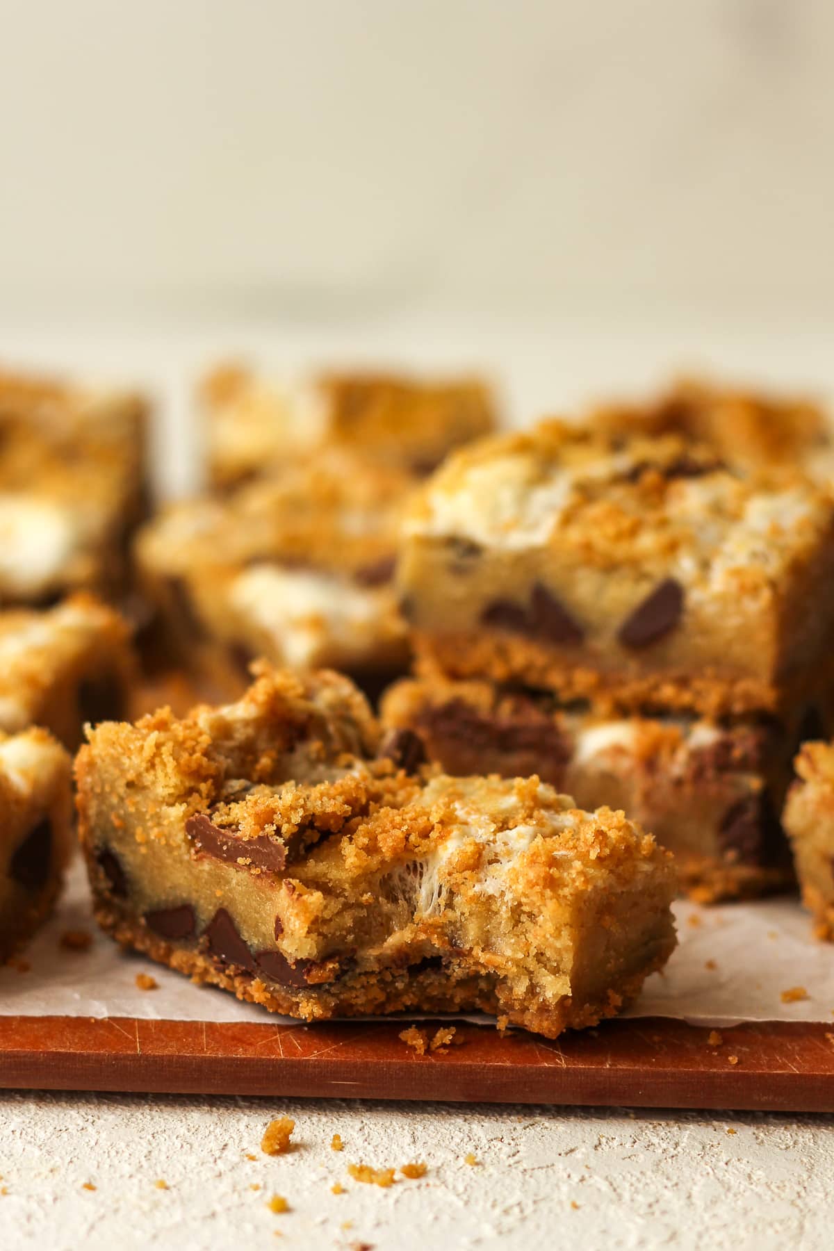 Side view of a s'mores cookie bar with a bite out of it and other bars in the background.