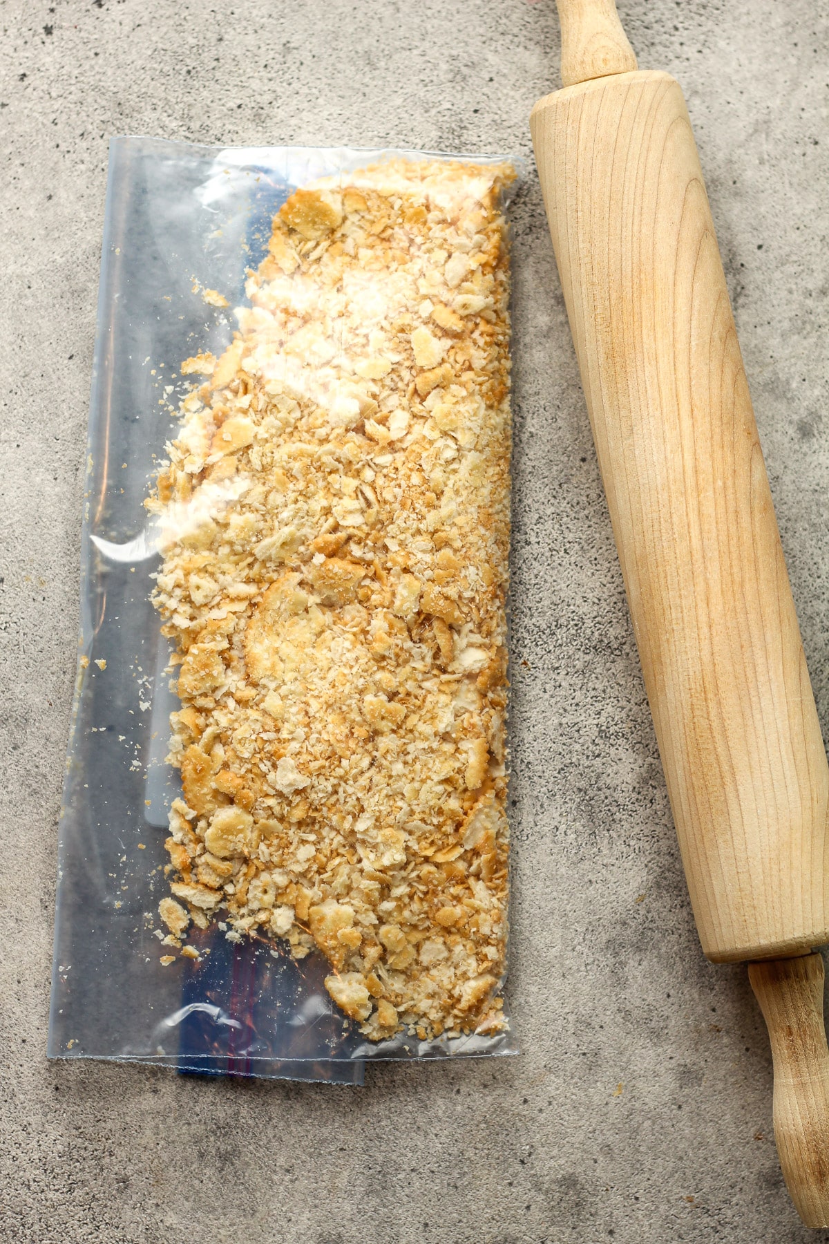 A bag of crushed crackers and a rolling pin.