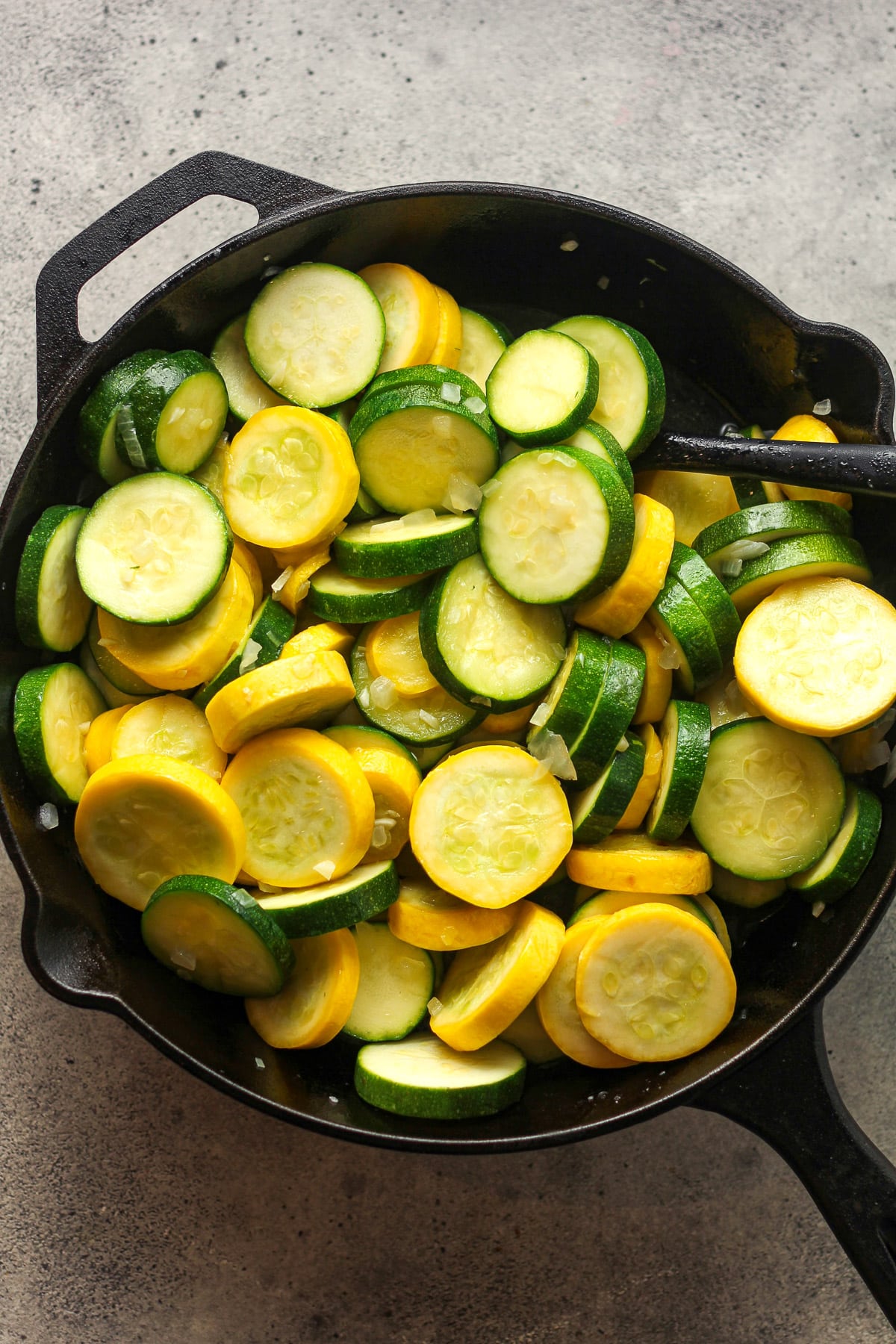 A cast iron skillet of sautéed squash and onion.