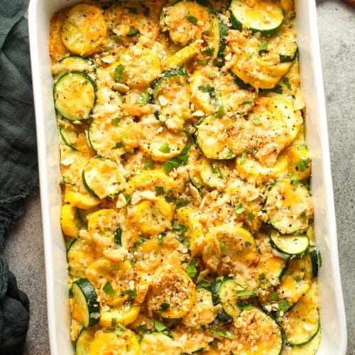 The baked squash casserole with a wooden spoon.