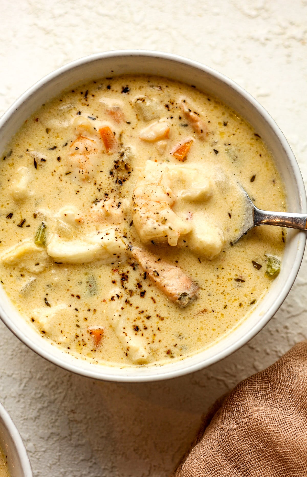 Closeup on a bowl of the seafood chowder with a spoon.