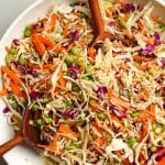 Closeup on a crunchy Asian cabbage salad with wooden spoons inside.