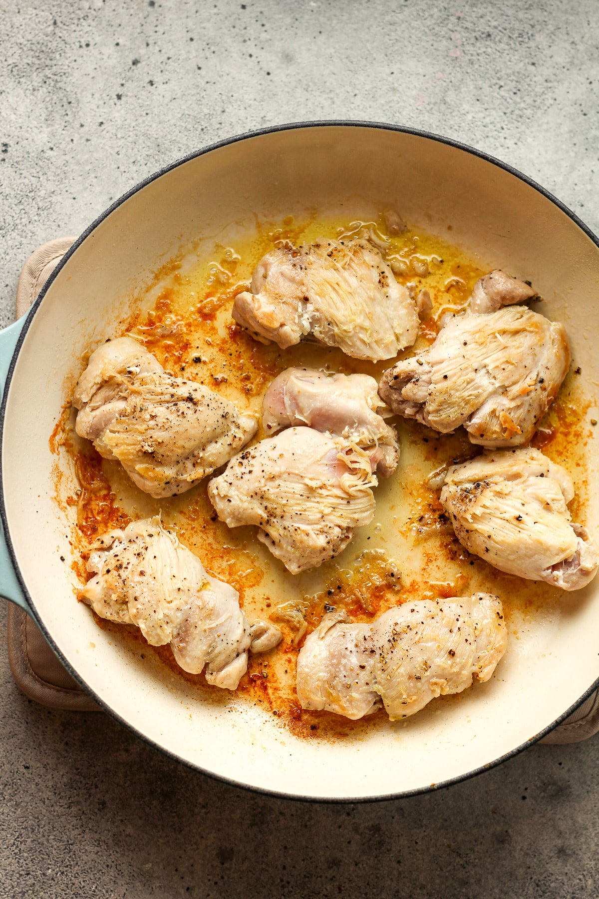 A skillet with browned chicken thighs.