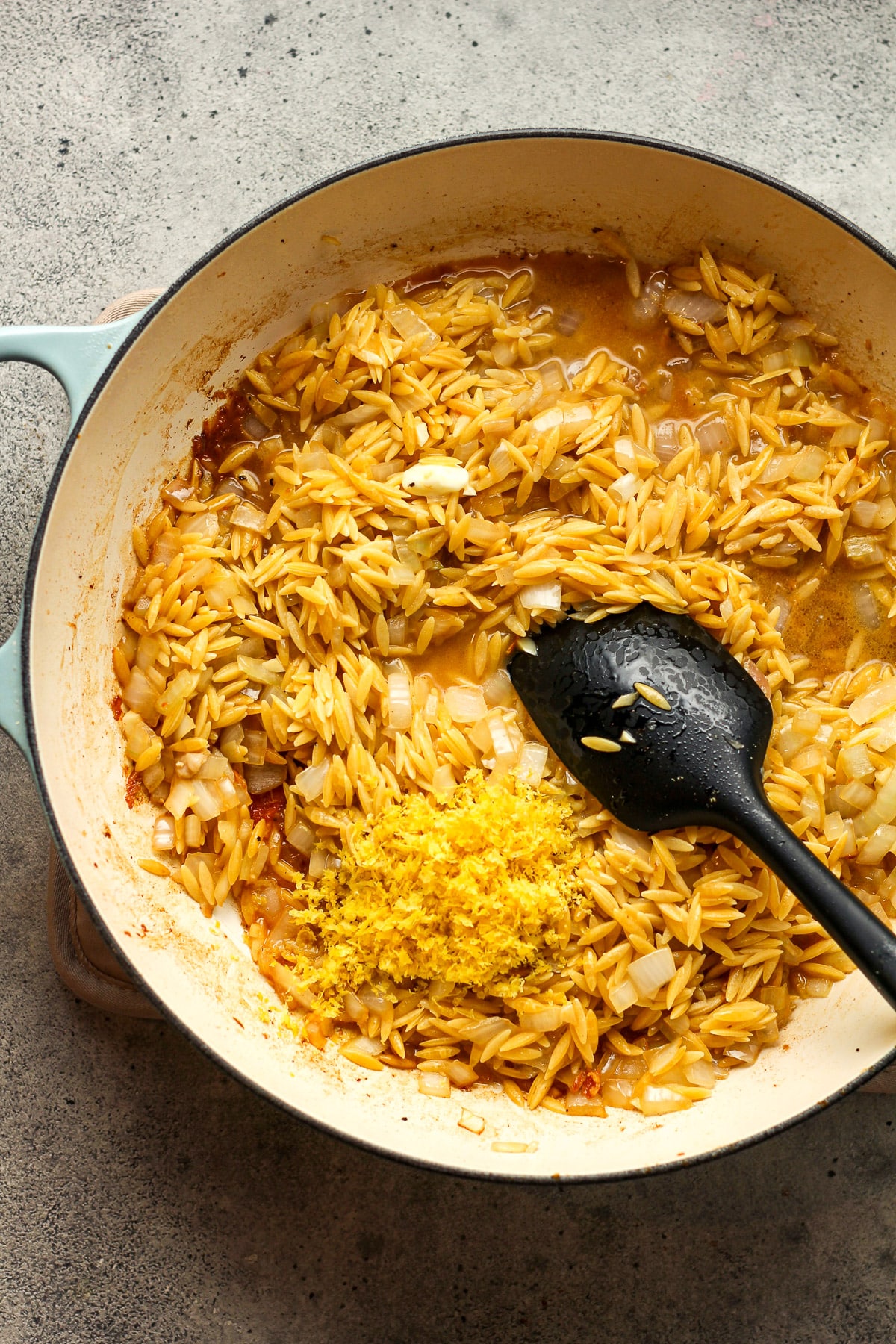 A skillet of the veggies, orzo, and lemon zest.