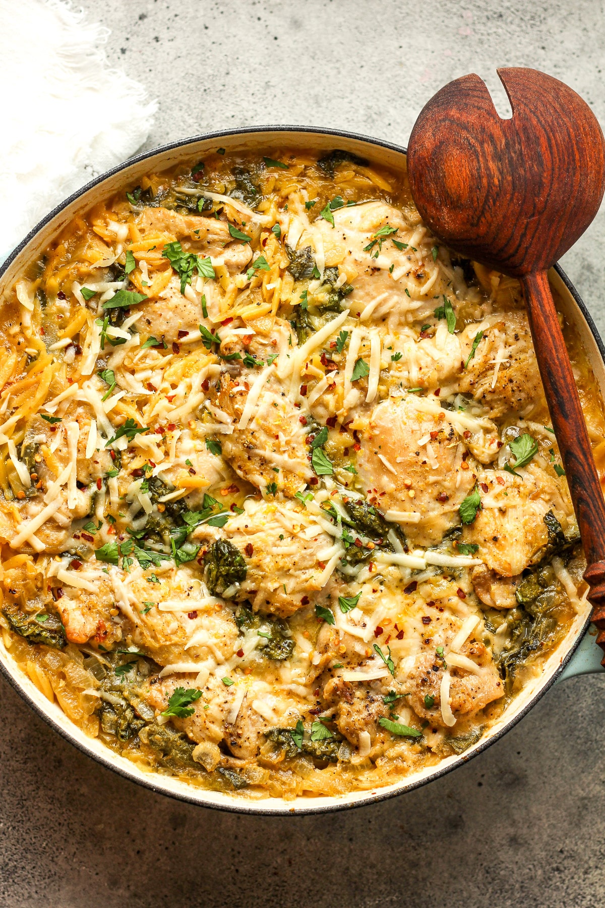 The finished chicken orzo pasta bake with a wooden spoon.