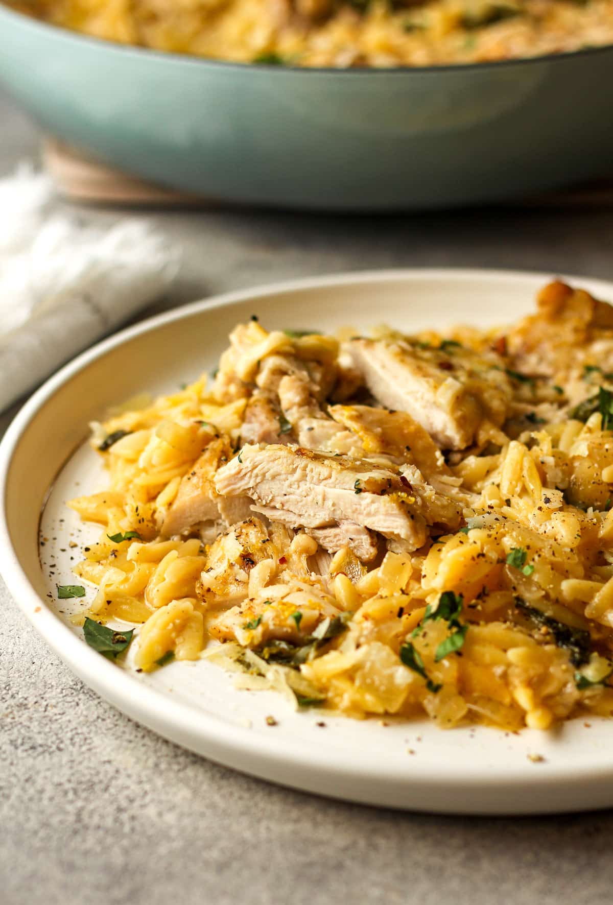 Side view of a serving of lemon chicken orzo with sliced chicken.