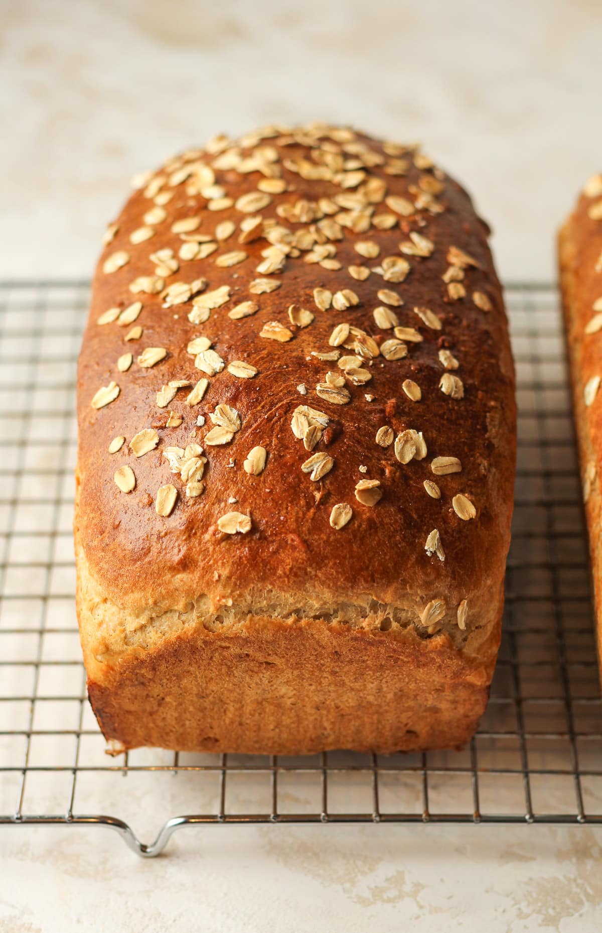 Side view of a loaf of oatmeal bread on a cooling rack.