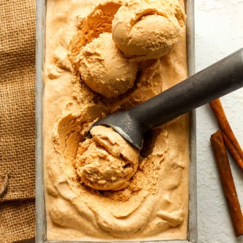 A pan of pumpkin ice cream with scoops inside.