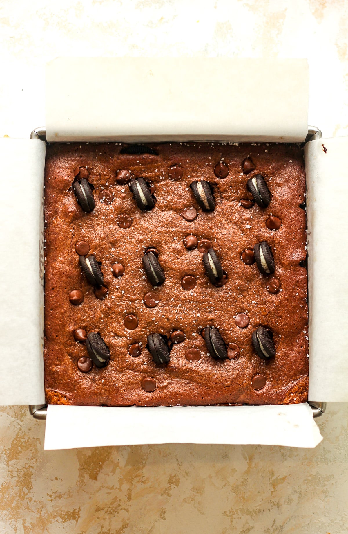 A pan of the baked slutty brownies with mini Oreo cookies on top.