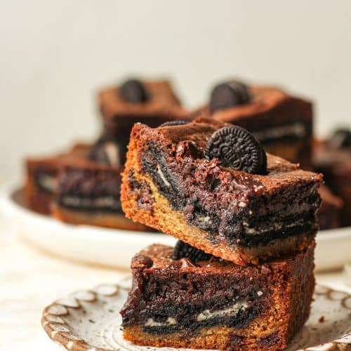 A small plate of two stacked Oreo cookie brownies, showing three layers.