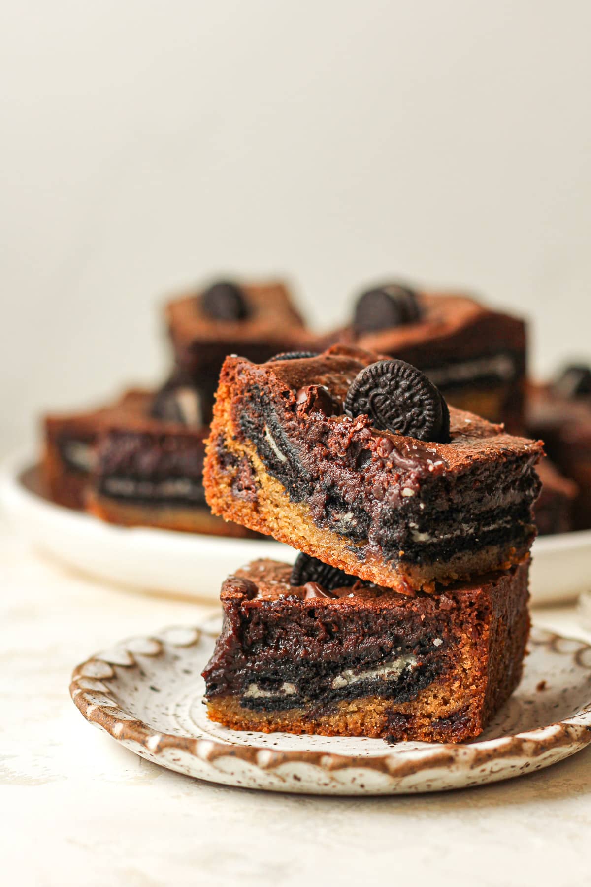 A small plate of two stacked Oreo cookie brownies, showing three layers.