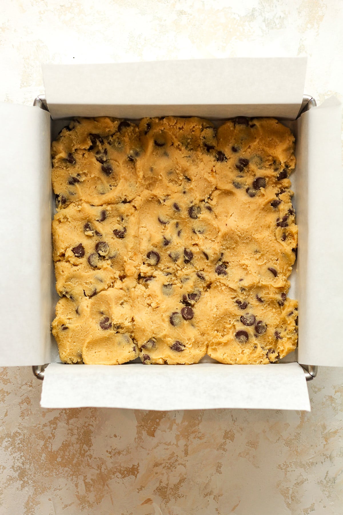 A square pan of the chocolate chip dough pressed in the bottom.