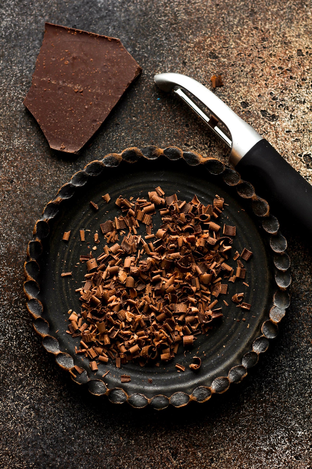 A plate of chocolate shavings with a potato peeler.