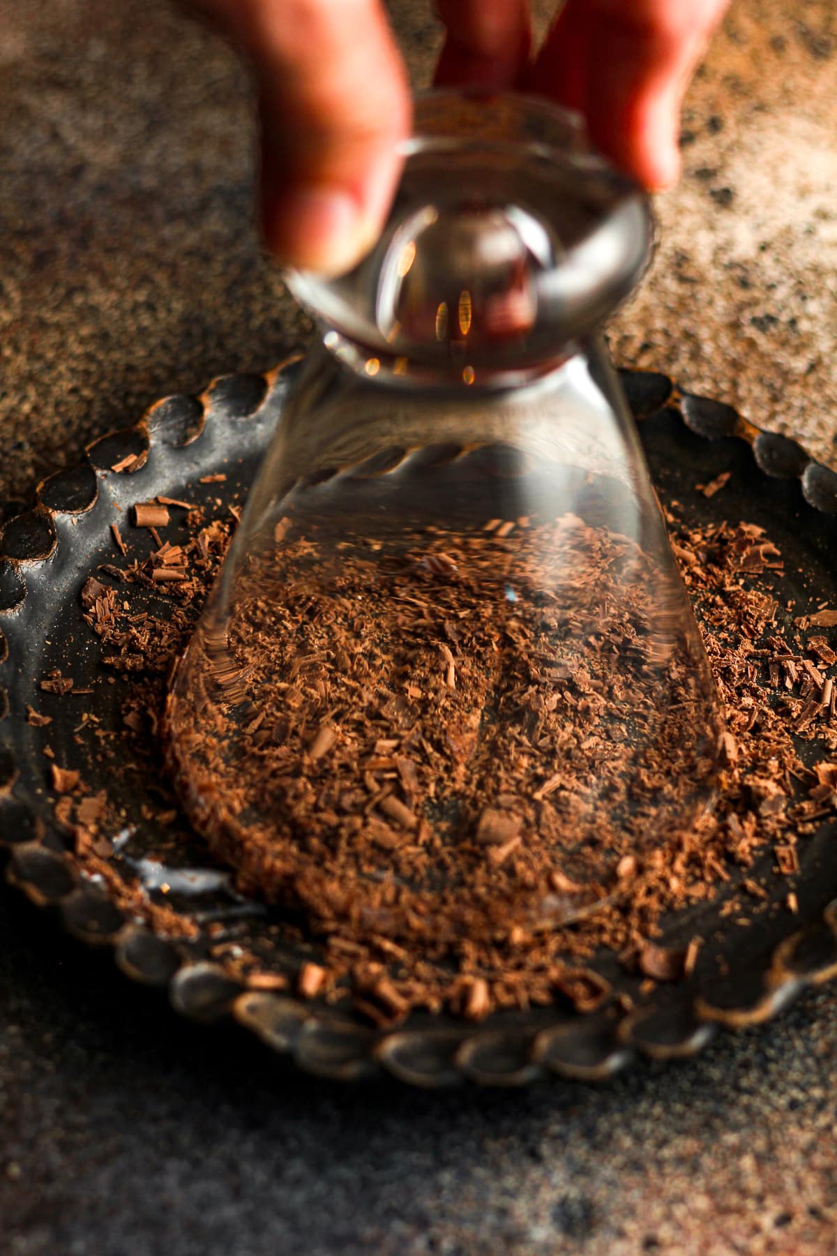 A glass upside down on a black plate of chocolate shavings.