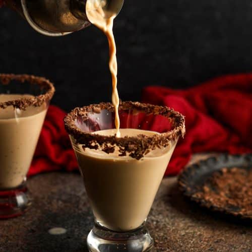 A cocktail shaker pouring chocolate martini in a glass.