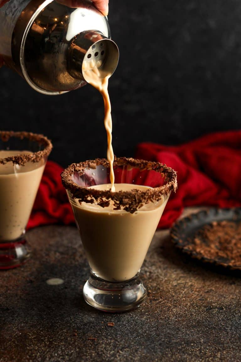 A cocktail shaker pouring chocolate martini in a glass.