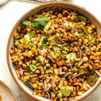 A bowl of black eyed pea dip with pickled jalapeños.