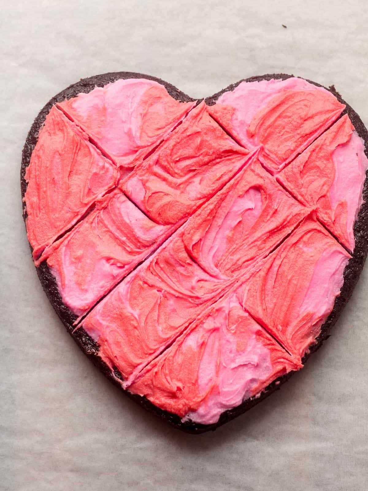 A heart shaped chocolate cake with pink and red buttercream frosting.