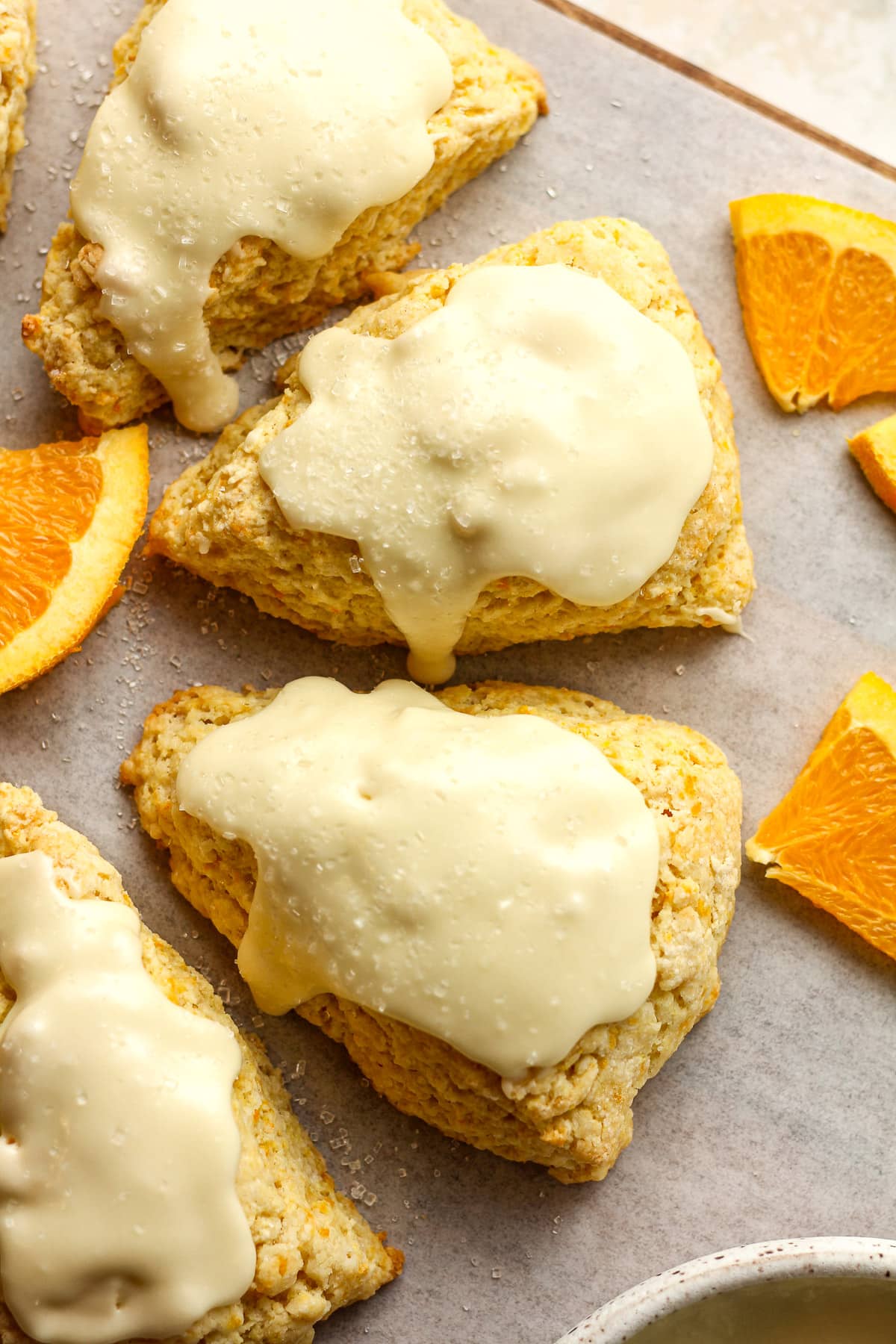 Overhead view of several orange scones with orange glaze.