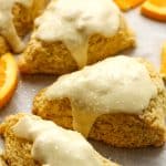 Side view of some flaky orange scones with glaze.