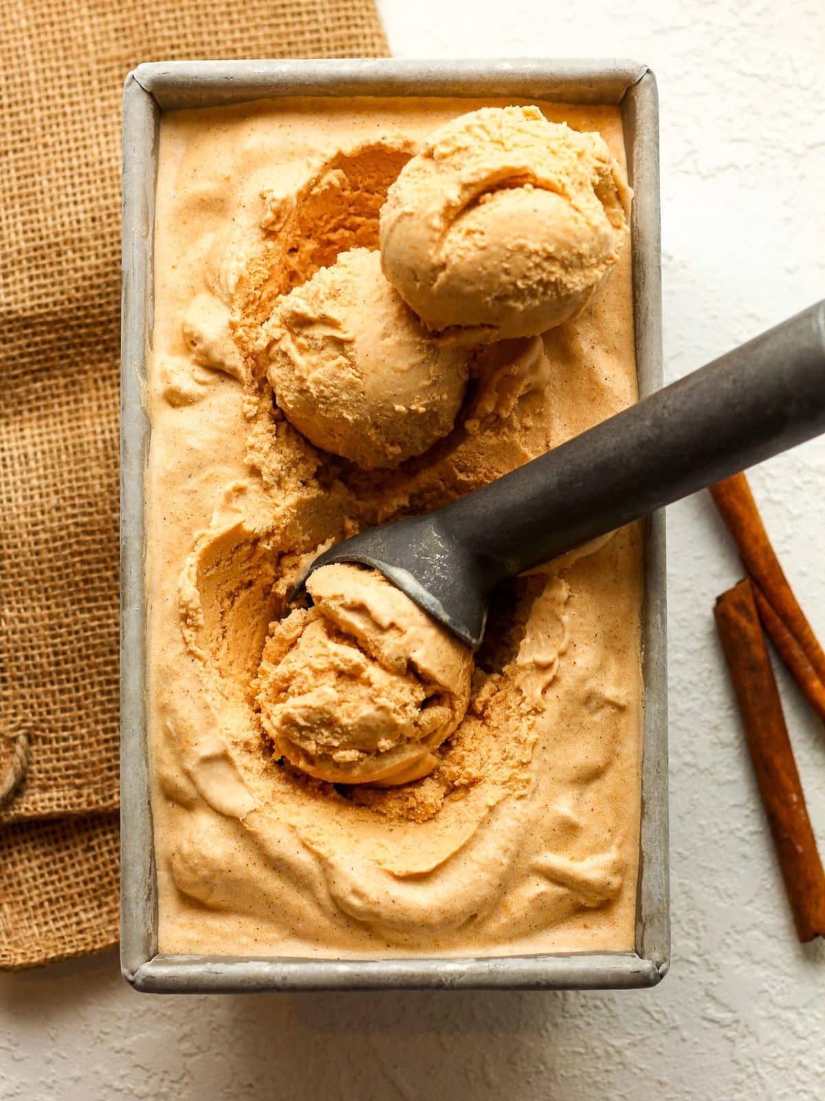 A pan of pumpkin ice cream with scoops inside.