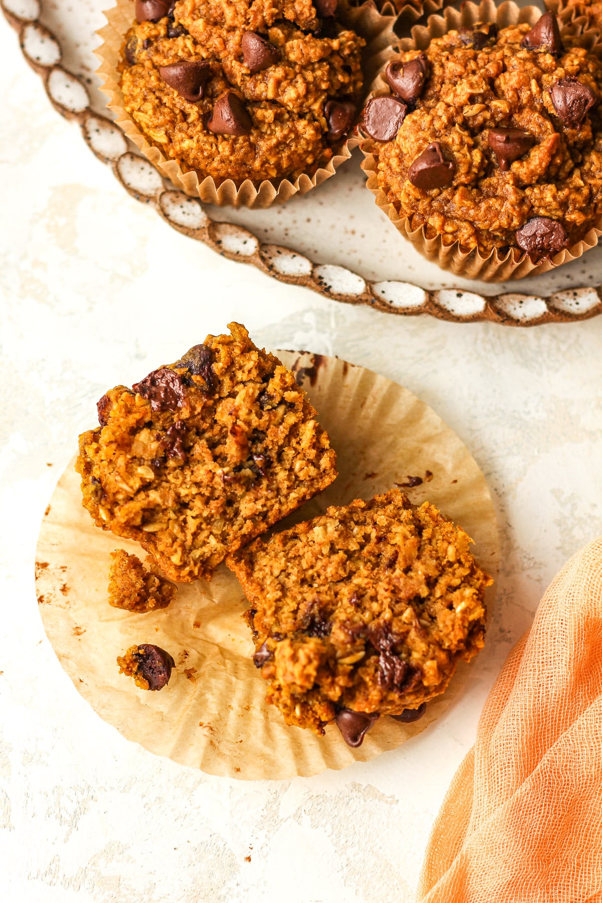 Overhead view of a halved pumpkin chocolate chip muffin on a liner.