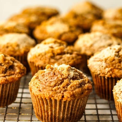 Side view of a wire rack of pumpkin muffins with streusel topping.