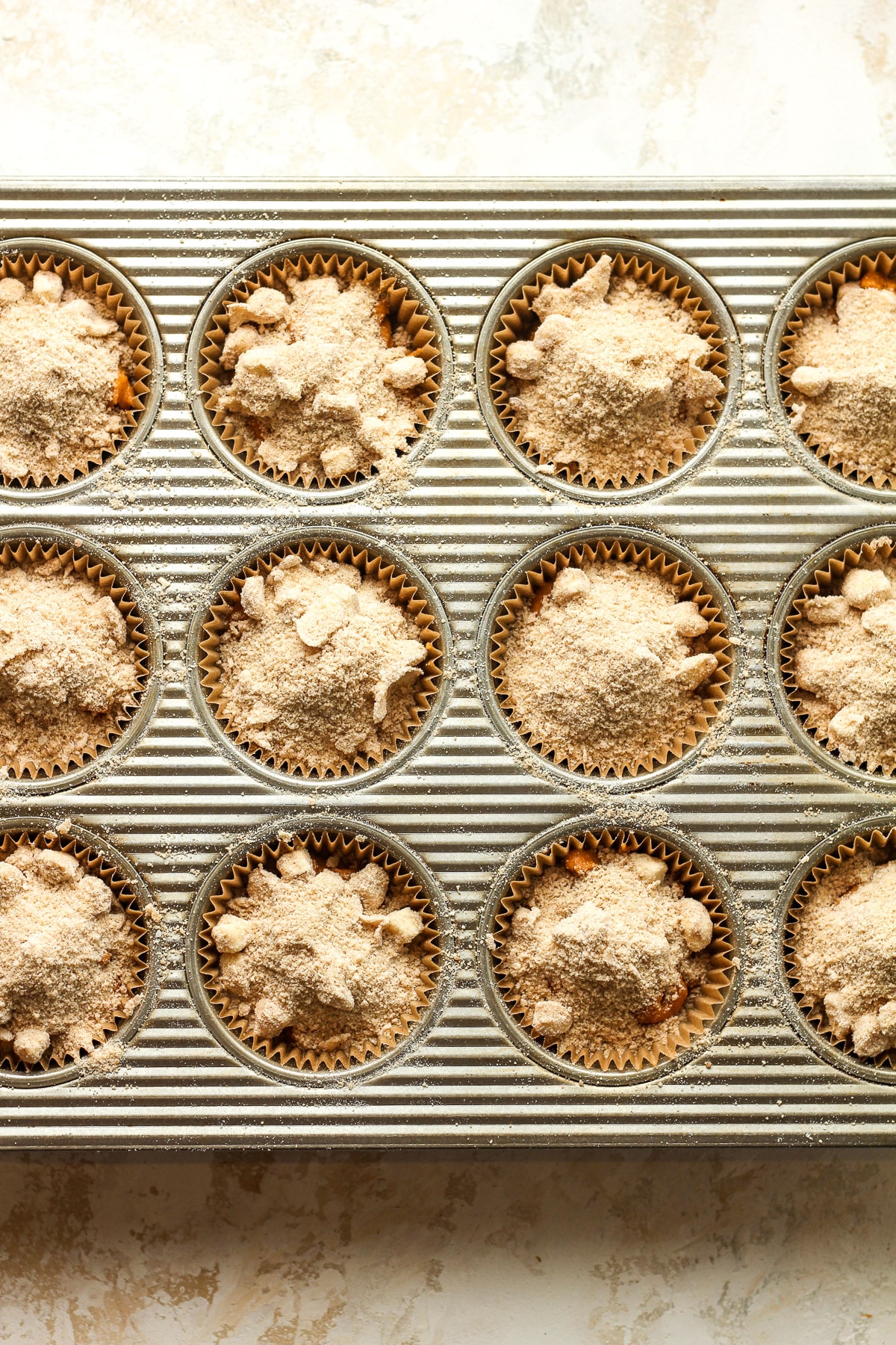 A muffin tin of the pumpkin batter with streusel on top.