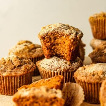 Some stacked pumpkin streusel muffins with a bite out of one muffin.