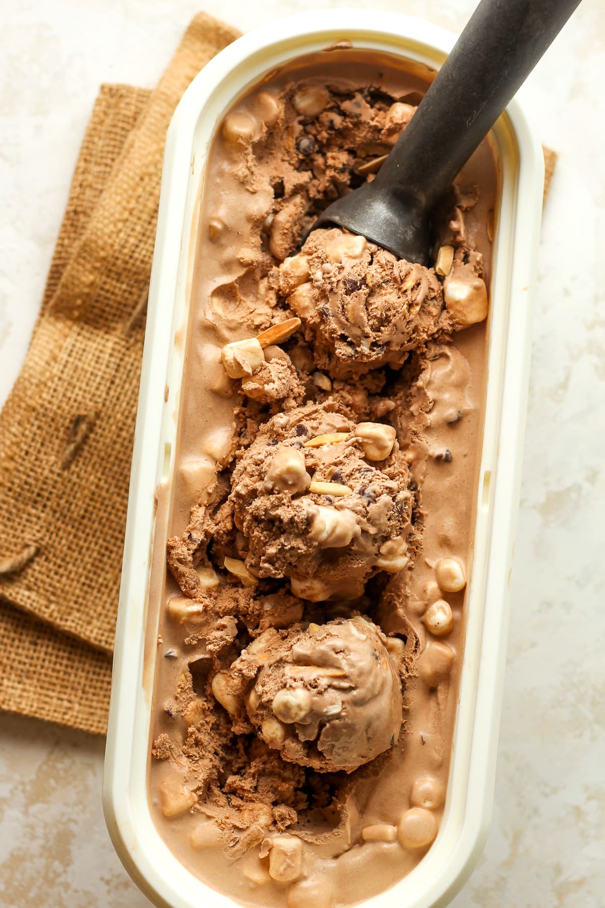 An oblong container of rocky road ice cream with three dips.