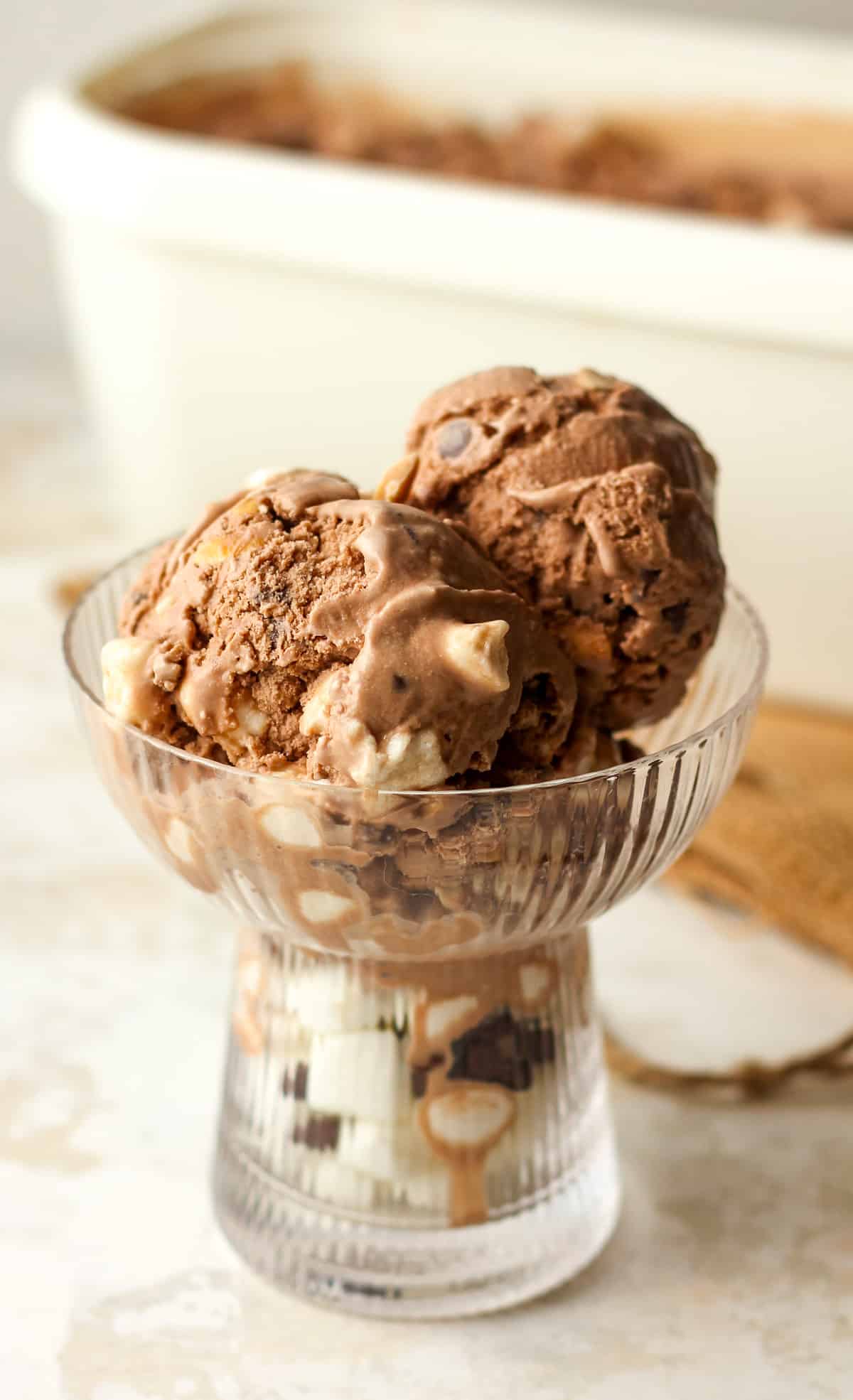 Side view of a glass dish of rocky road ice cream.