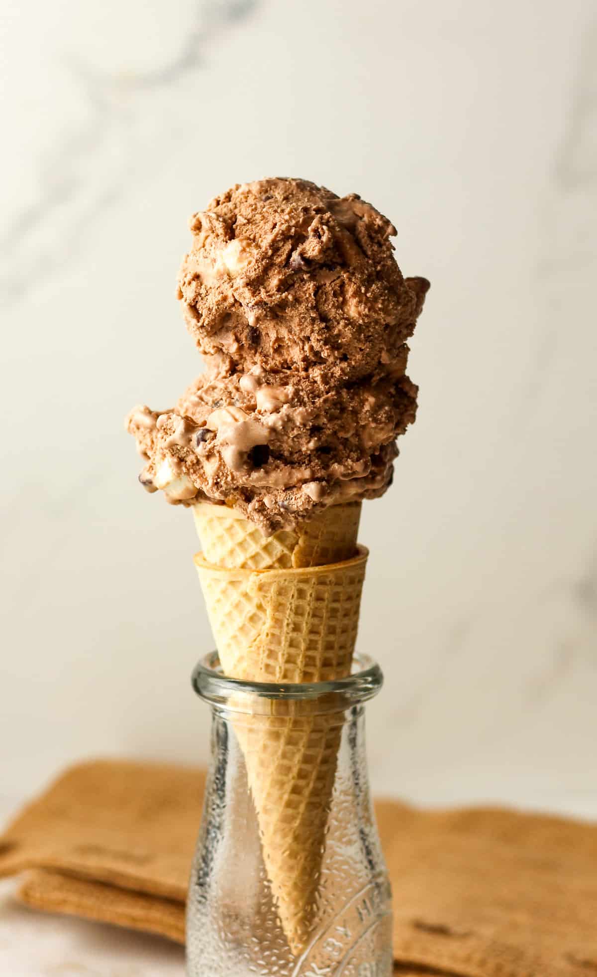 Side view of a sugar cone of rocky road ice cream.