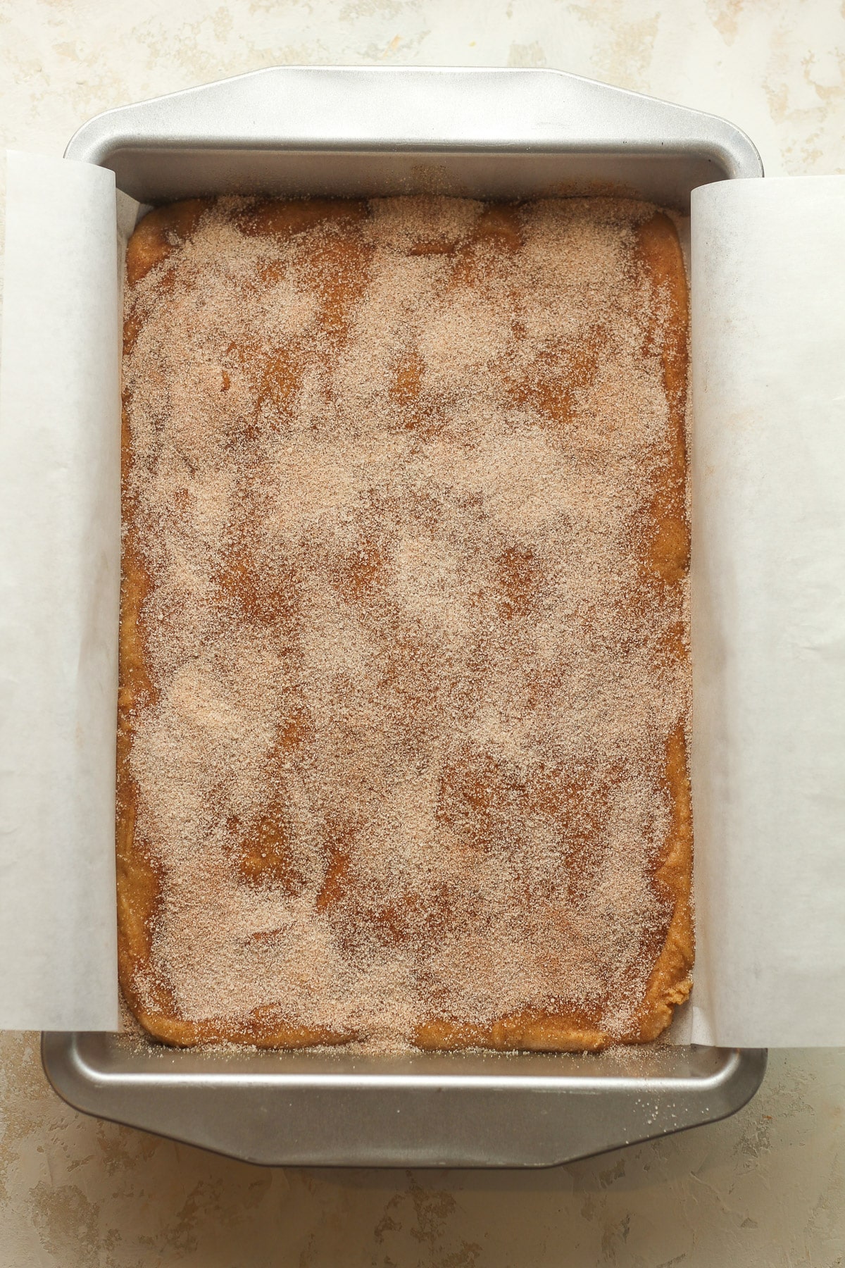 The pan with dough and sugar and cinnamon topping.