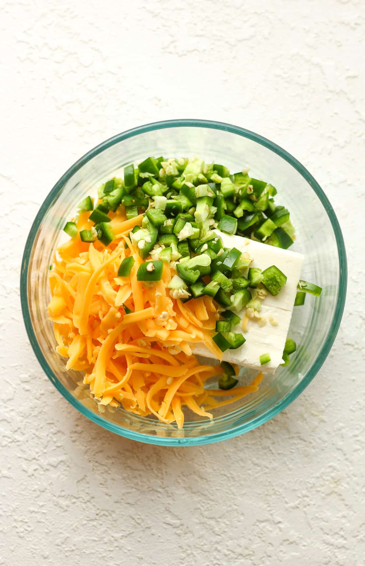 A small bowl with cream cheese, cheddar cheese, and diced jalapeños.