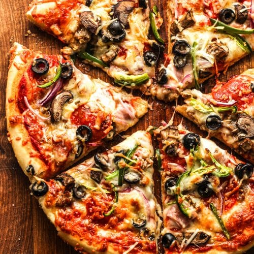 Overhead view of a sliced pizza with meat and veggies.