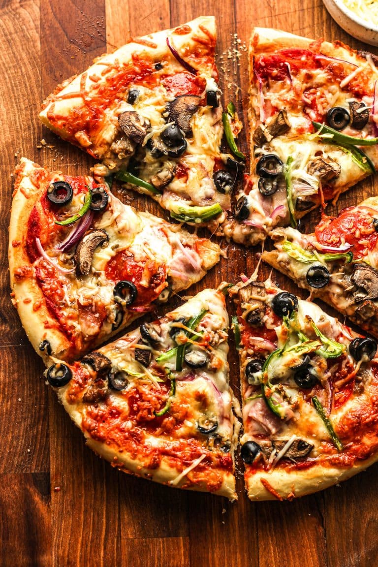 Overhead view of a sliced pizza with meat and veggies.