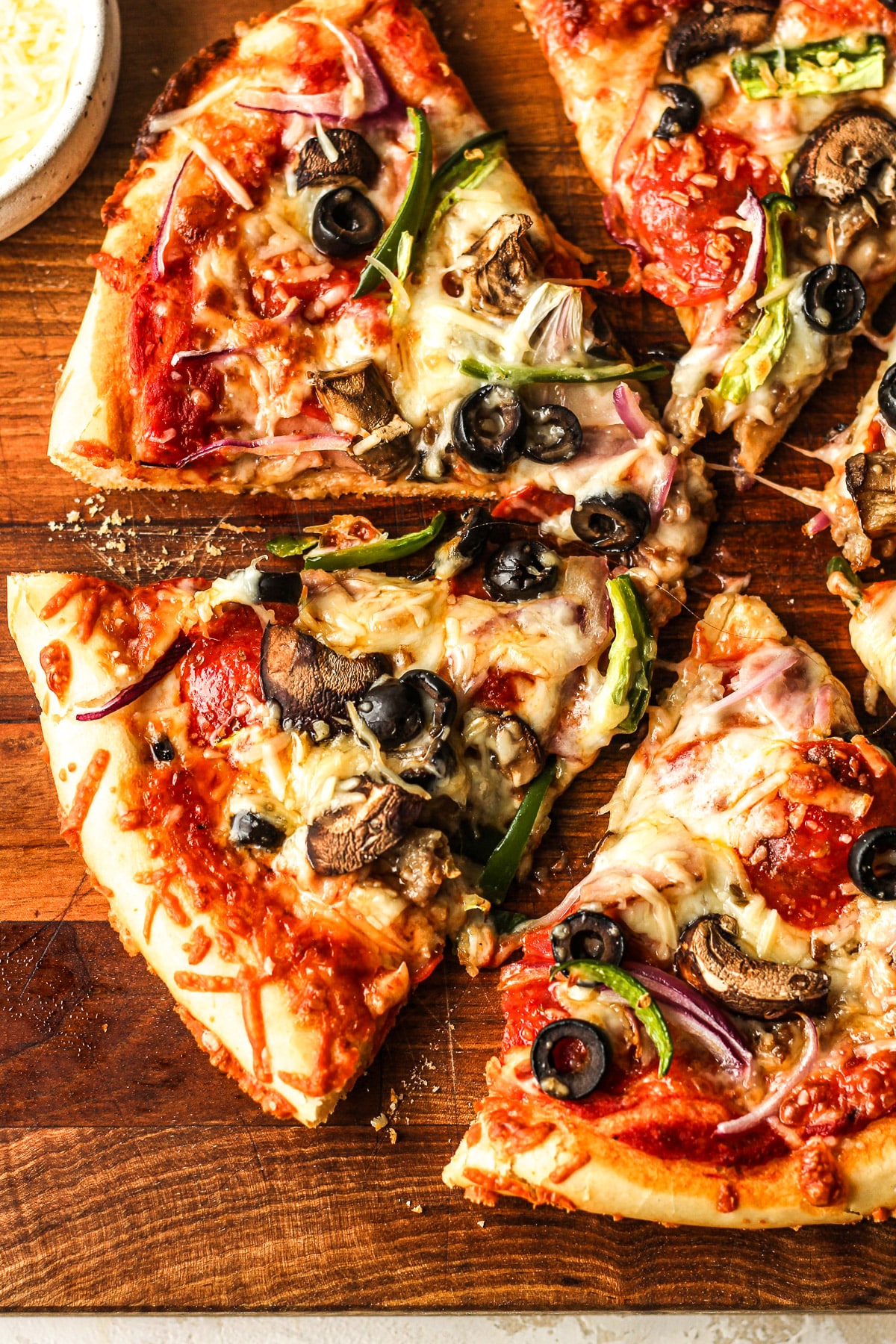 A sliced Supreme pizza on a wooden board.