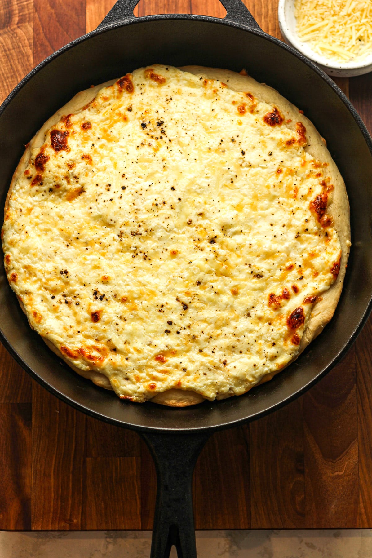 A skillet with a baked three cheese pizza.