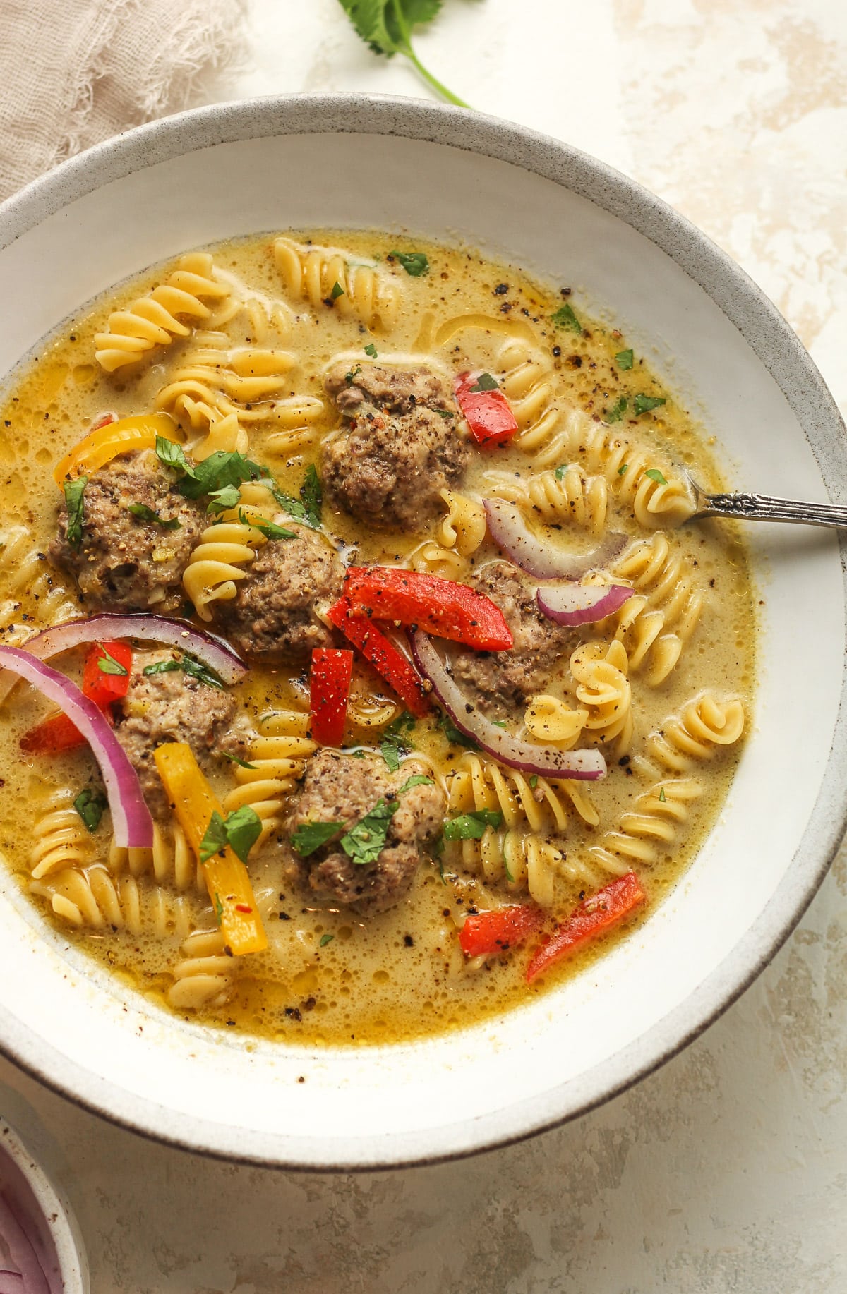 A bowl of the meatball soup with rotini noodles.