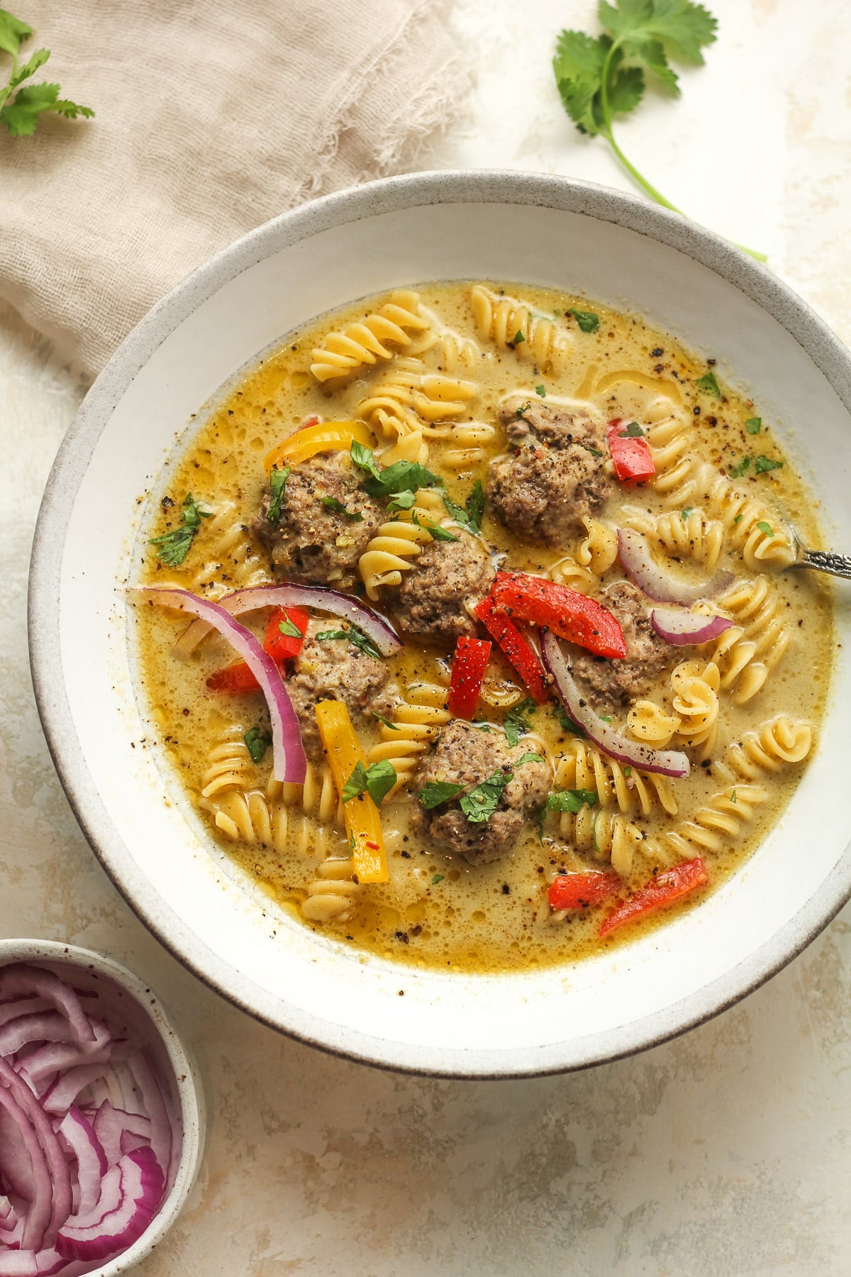 Overhead view of a shallow bowl of Thai soup with meatballs.