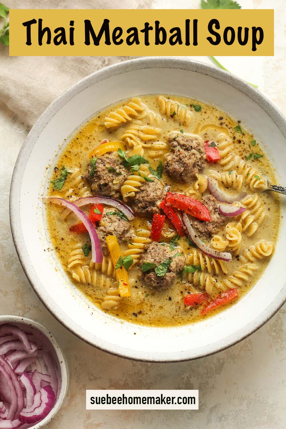 A bowl of Thai meatball soup with rotini noodles.