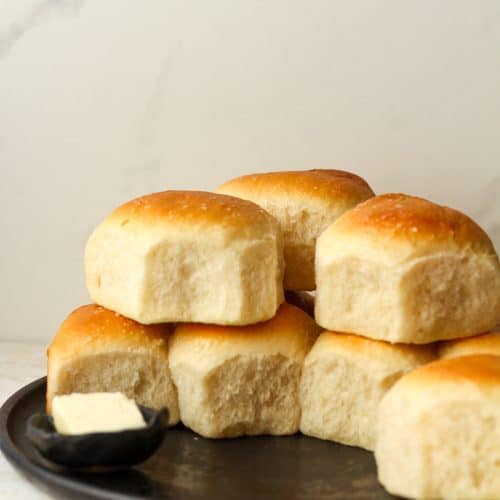 Side view of stacked dinner rolls on a plate.