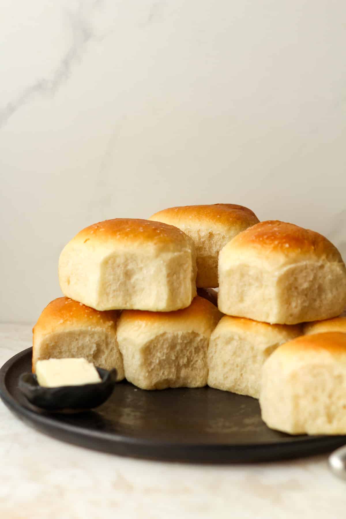 Side view of stacked dinner rolls on a plate.