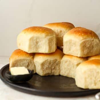 Side view of a plate of stacked dinner rolls.