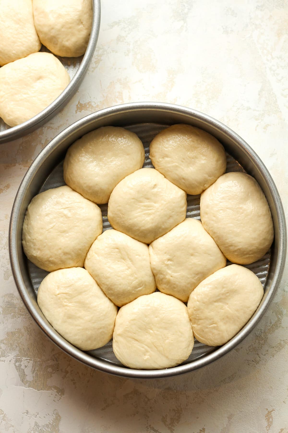 A round pan with 10 small dough rounds.